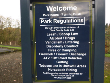 Sign – park hours 7 am to dusk – dogs on leash – no alcohol, drugs, firearms, fires, fireworks, littering, smoking